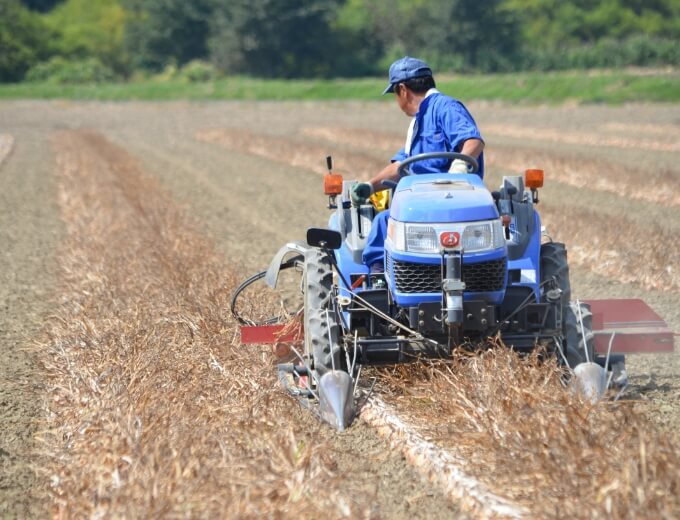 農夫がトラクターで作業をする写真